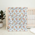 Monster Trucks baby blanket personalized with Ryder, draped over a wooden crib in a bright nursery.