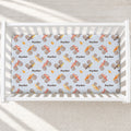 Monster Trucks personalized crib sheet with Ryder lettering and colorful watercolor trucks on pale blue, fitted in a white crib.
