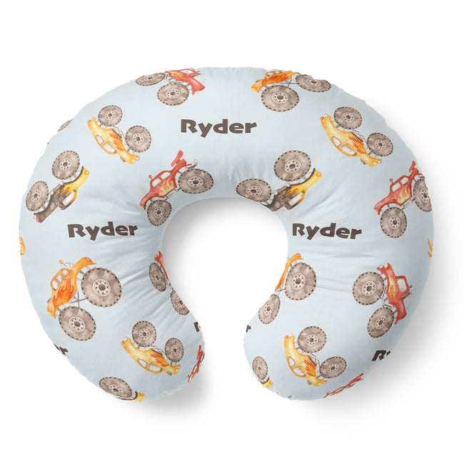 Top view of the Monster Trucks nursing pillow cover with brown Ryder lettering and watercolor trucks with oversized taupe tires.