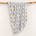 Monster Trucks swaddle blanket personalized with Ryder, draped over a wooden branch, featuring colorful watercolor trucks on pale blue.