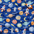 A close-up of a blue fabric with a colorful space-themed print featuring planets, stars, rockets, astronauts, and crescent moons, with the word 'SCOUT' repeated across the design.