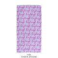 A personalized beach towel featuring a repeating pattern of the name 'Kayleigh' in bright pink cursive script on a light lavender background. The brand name 'CAIDEN DESIGNS' is printed below the product on a white background.