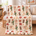 A fleece throw blanket with a Western-themed 'SCOUT' print is draped over a white sofa in a bright, sunlit living room. The blanket features a cream background with repeating illustrations of green cacti, brown cowboy boots, red cowboy hats, orange horseshoes, and gold stars, with the word 'SCOUT' printed repeatedly.