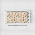 A crib mattress fitted sheet with a western-themed print of cowboy boots, hats, cacti, and lasso on a cream background, shown inside a white wooden crib. Text below reads 'Pattern shown horizontally, please specify if you prefer vertical.