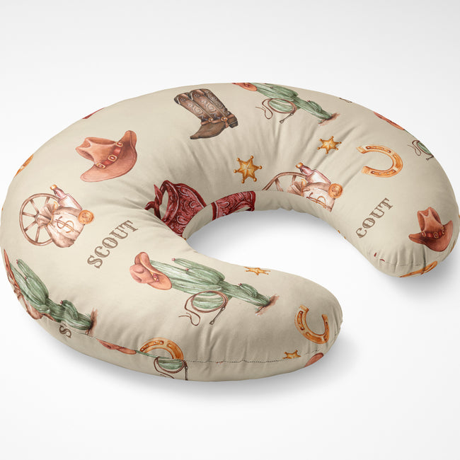 Wild West nursing pillow cover personalized with Scout, shown on a curved pillow with watercolor cowboy motifs on cream.