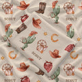 Folded Wild West swaddle blanket showing Scout personalization, cowboy illustrations and stitched edging on cream fabric.
