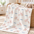 Personalized Pig Baby Blanket. Sweet pink pigs with blue bows surround a custom name on a soft cream background.