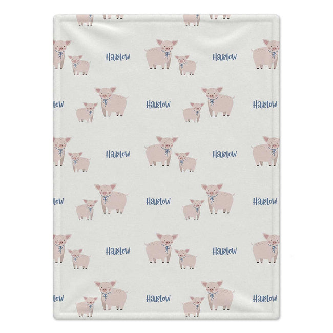 Personalized Pig Baby Blanket. Sweet pink pigs with blue bows surround a custom name on a soft cream background.