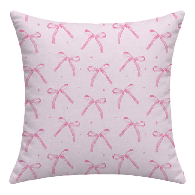 Back of a blush pink throw pillow featuring a repeating watercolor bow pattern and tiny pink sparkles without lettering.