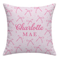 Blush pink throw pillow with watercolor bows and tiny sparkles surrounding the centered name Charlotte Mae in large pink lettering.