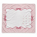 A baby milestone blanket with a pink and white gingham border, a scalloped pink frame, ribbon-bow details, and a central white area printed with numbers 1 through 12 and the word 'months' for tracking birth months.