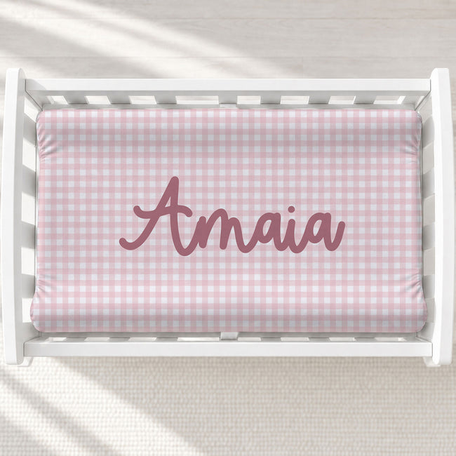 Personalized pink gingham baby changing pad cover with name Amaia centered.