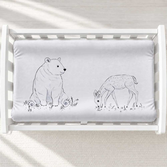 A personalized baby changing pad cover featuring a gray and white illustration of a polar bear and a deer.