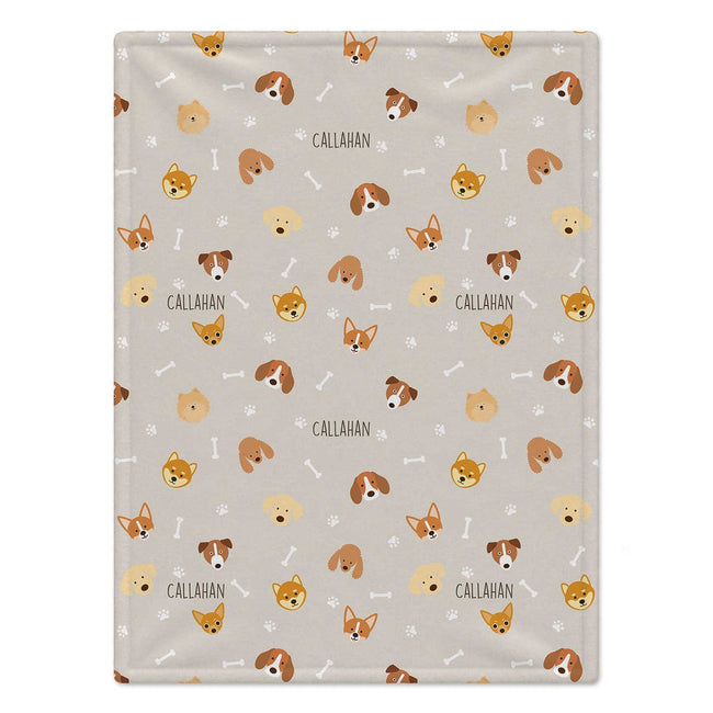 A personalized baby blanket featuring a repeating pattern of cartoon dog faces, bones, and paw prints on a light beige background. The name 'CALLAHAN' is printed in black text next to several dog illustrations.