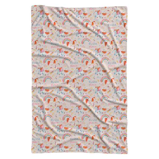 A rectangular blanket with a repeating pattern of pink unicorns, colorful rainbows, and the name 'ELIZA' printed repeatedly, shown flat against a white background.