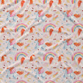A close-up of a fabric surface with a repeating whimsical print featuring unicorns, rainbows, stars, hearts, and crescent moons on a light warm background.