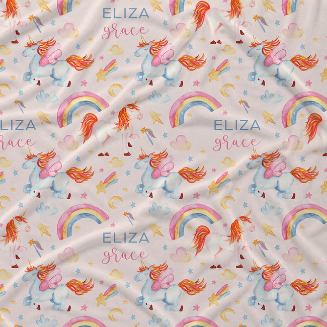 A close-up of a fabric surface with a repeating whimsical print featuring unicorns, rainbows, stars, hearts, and the text 'ELIZA grace' in blue and pink script.