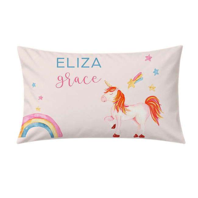 A personalized rectangular pillow featuring a watercolor-style white unicorn with a pink and orange mane, a rainbow, stars, and the names 'ELIZA' and 'grace' printed on a pale pink background.