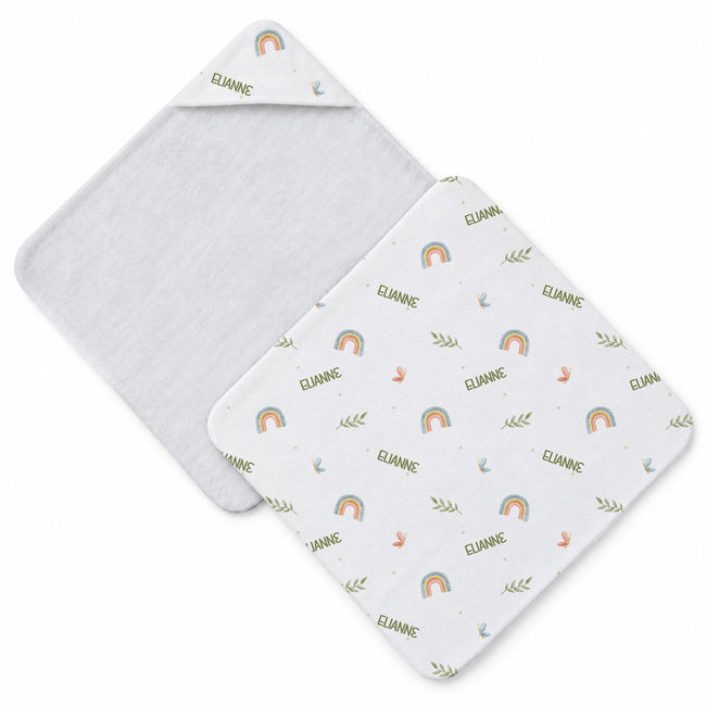 Two square baby hooded towels on a white background with a white background with a repeating pattern of small rainbows, leaves, stars, and the name 'ELIANNE' in olive green.