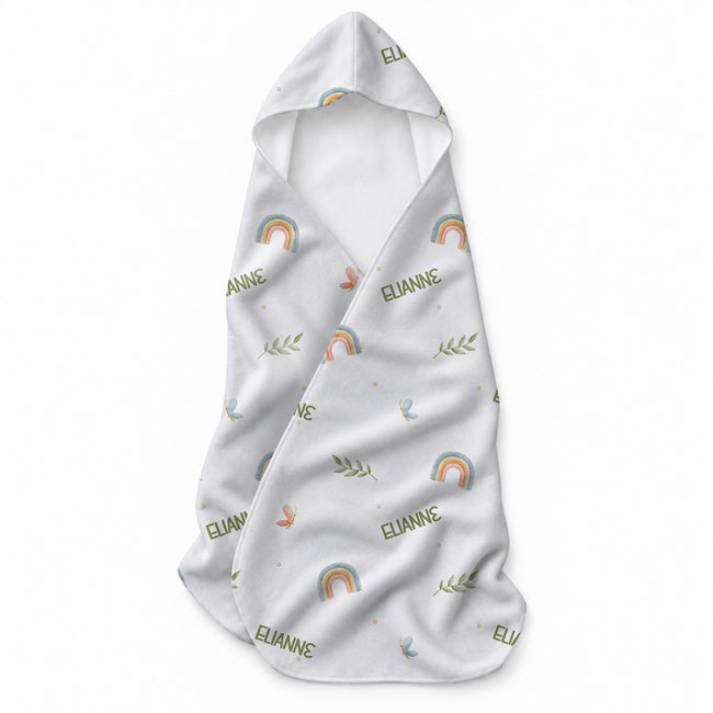 White hooded towel with muted blue, peach, and gold rainbows, small butterflies, green leafy sprigs, and the name Elianne.