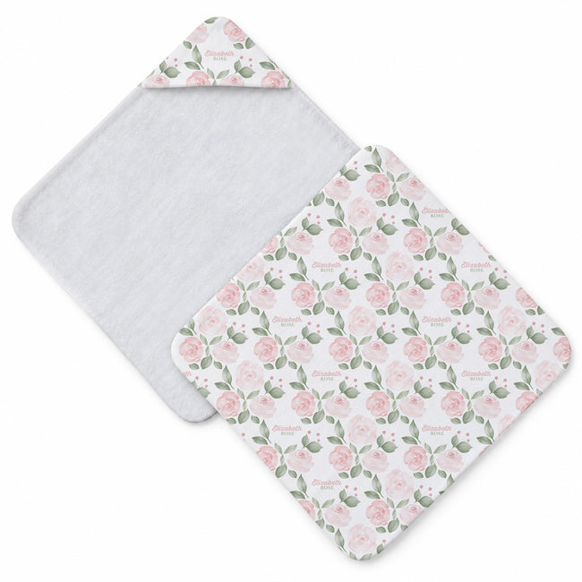 A baby hooded towel set shown on a white background, featuring one solid white towel and one white towel with a pink rose and green leaf floral pattern.