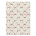 A rectangular cream-colored blanket featuring a repeating pattern of red ribbon bows and the word 'Avery' in cursive script.