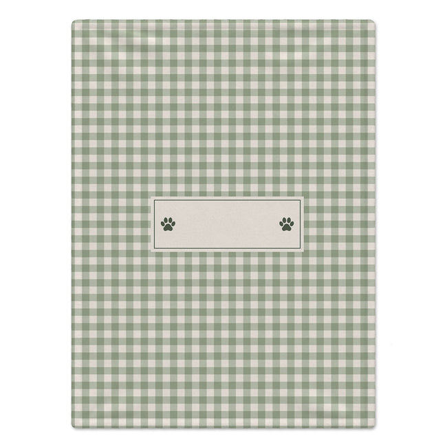 A personalized dog blanket featuring a green and white gingham checkered pattern, featuring a central cream-colored label with two dark green paw prints.