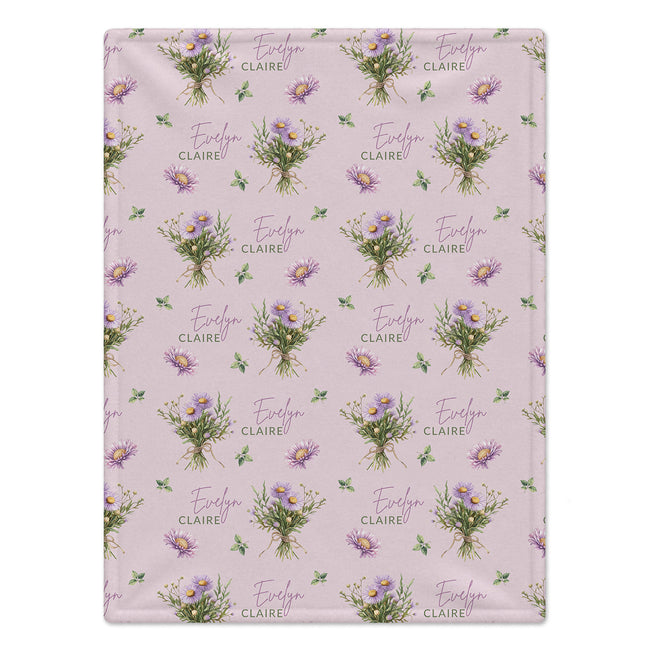 Mauve-pink blanket with lavender aster bouquets, yellow flower centers, green leaves, and the name Evelyn Claire.