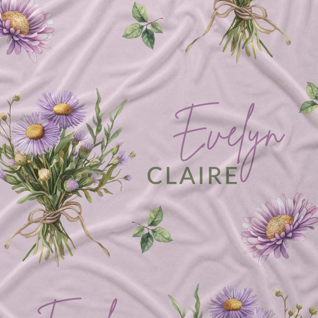 Mauve-pink fabric with lavender aster bouquets, yellow flower centers, green leaves, and the name Evelyn Claire.