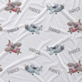 A white fabric blanket or throw featuring a repeating pattern of watercolor-style airplanes and the name 'PARKER' in gray lettering.