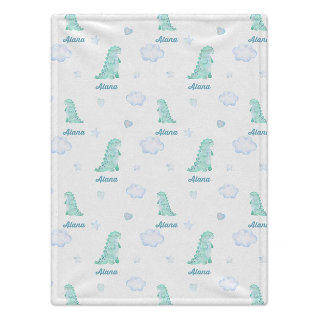 A personalized baby blanket featuring a repeating pattern of light blue watercolor dinosaurs, clouds, stars, and the name 'Alana' printed in blue script.