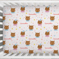 A fitted crib mattress cover with a repeating pattern of cartoon owls, the name 'Samantha', and small hearts, stars, and flowers on a white background, shown inside a white crib.