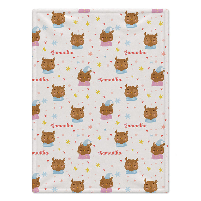 A personalized baby blanket featuring a repeating pattern of cartoon owl faces and the name 'Samantha' in pink script on a cream background.