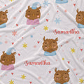 A white fabric with a printed pattern of sleeping owls, colorful stars, hearts, and the name 'Samantha' in pink script.