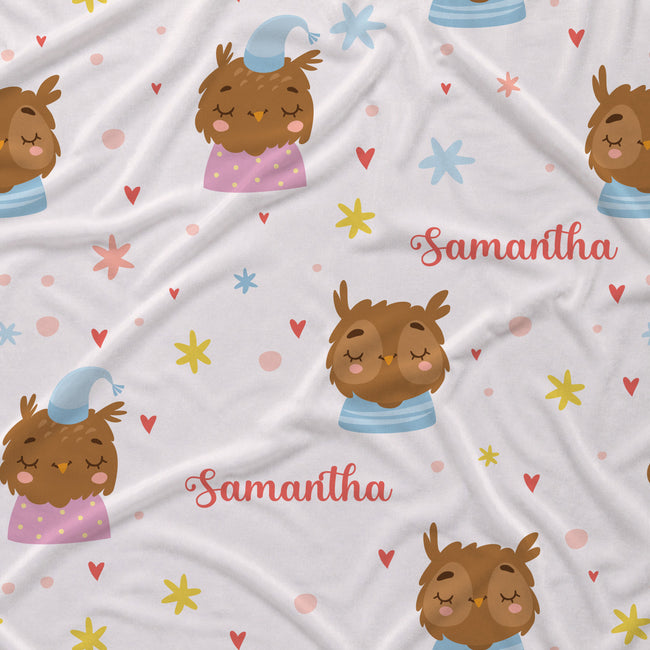 A white fabric with a printed pattern of sleeping owls, colorful stars, hearts, and the name 'Samantha' in pink script.