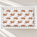 A white crib mattress fitted with a printed sheet featuring a repeating pattern of sleeping sloths, crescent moons, stars, and the name 'shionna' in brown script.