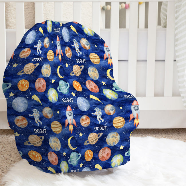 Space Explorers baby car seat cover personalized with Scout, featuring watercolor planets, rockets, and astronauts on navy in a bright nursery.