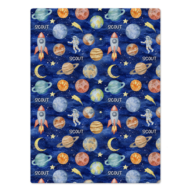 Space Explorers baby blanket personalized with Scout, draped over a wooden crib and featuring watercolor planets and rockets on navy.
