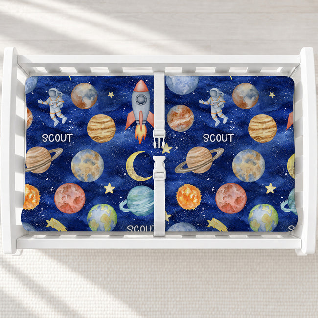 Space Explorers changing pad cover personalized with Scout, featuring watercolor planets, rockets, and astronauts on a navy starry background.