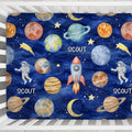 Close-up of the Space Explorers crib sheet personalized with Scout, featuring watercolor planets, rockets, and astronauts on navy inside a white crib.