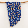 Space Explorers personalized swaddle blanket draped over a wooden branch, with Scout lettering and watercolor planets and rockets on navy.