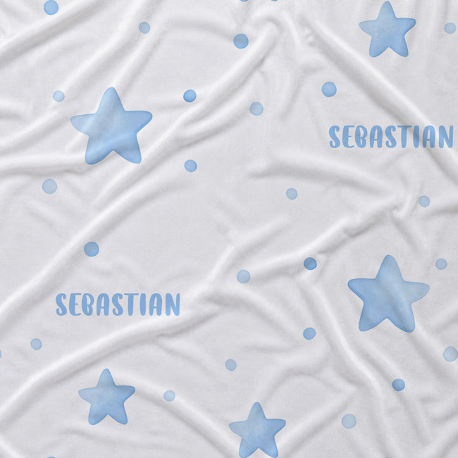 White fabric with a pattern of light blue stars, dots, and the name 'SEBASTIAN' printed in blue, shown as a close-up texture shot.