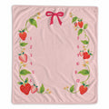 A baby milestone blanket featuring a decorative border of illustrated strawberries, green leaves, small yellow flowers, and red bow accents, with red numbers 1 through 12 arranged along the left and right sides.