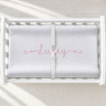 A white changing table with a personalized changing pad cover featuring a personalization with a swirly font with the name Lucey centered on the cover.