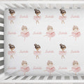 A baby crib sheet featuring a repeating pattern of ballerina illustrations and the name 'Isabella' in pink script, shown inside a white wooden crib.