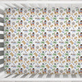 A crib mattress cover with a colorful pirate-themed pattern featuring the name 'Archer James' repeated, shown inside a white wooden crib.