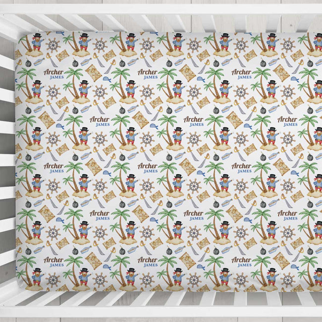 A crib mattress cover with a colorful pirate-themed pattern featuring the name 'Archer James' repeated, shown inside a white wooden crib.