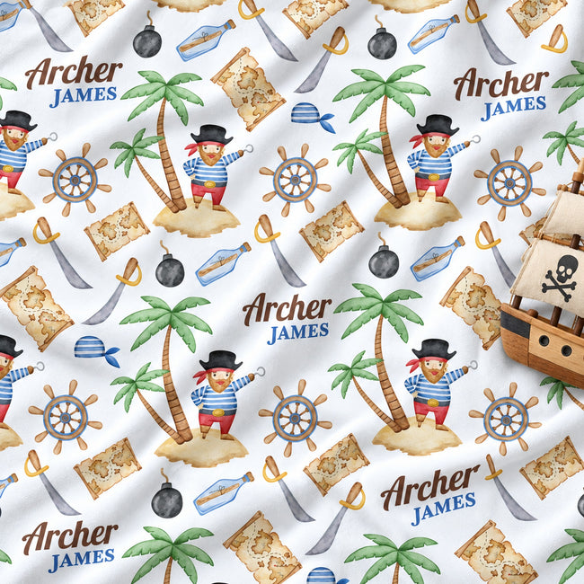 Custom printed blanket featuring a pirate theme with palm trees, treasure maps, ship's wheels, swords, and a pirate ship. The design includes the personalized name 'Archer James' in blue text.