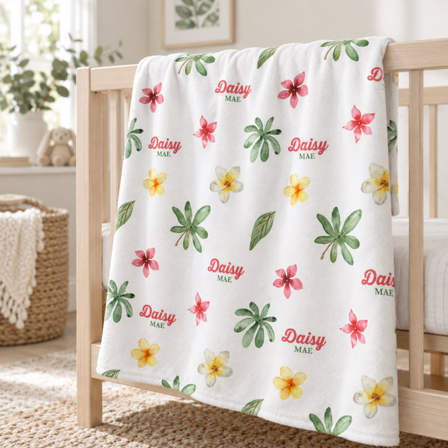 Personalized Tropical Flower Baby Blanket. Watercolor tropical flowers in pink and yellow mingle with green leaves around a custom name.
