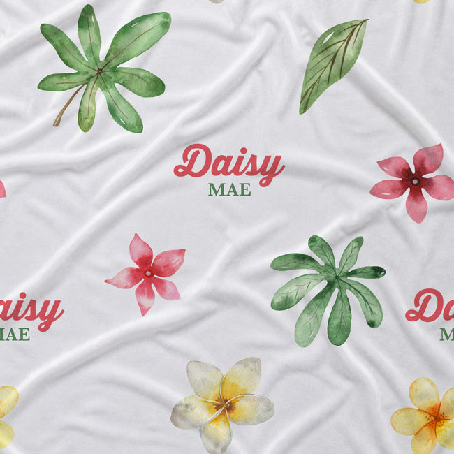 White fabric with a tropical watercolor print featuring green leaves, pink and yellow flowers, and the text 'Daisy MAE' repeated across the surface.